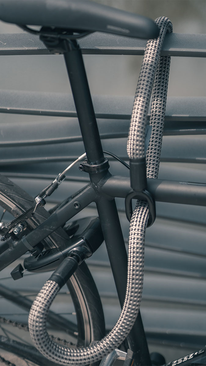 Fahrrad mit Rahmenschloss an festem Gegenstand gesichert durch flexible Fahrradschloss-Verlängerung aus Textil