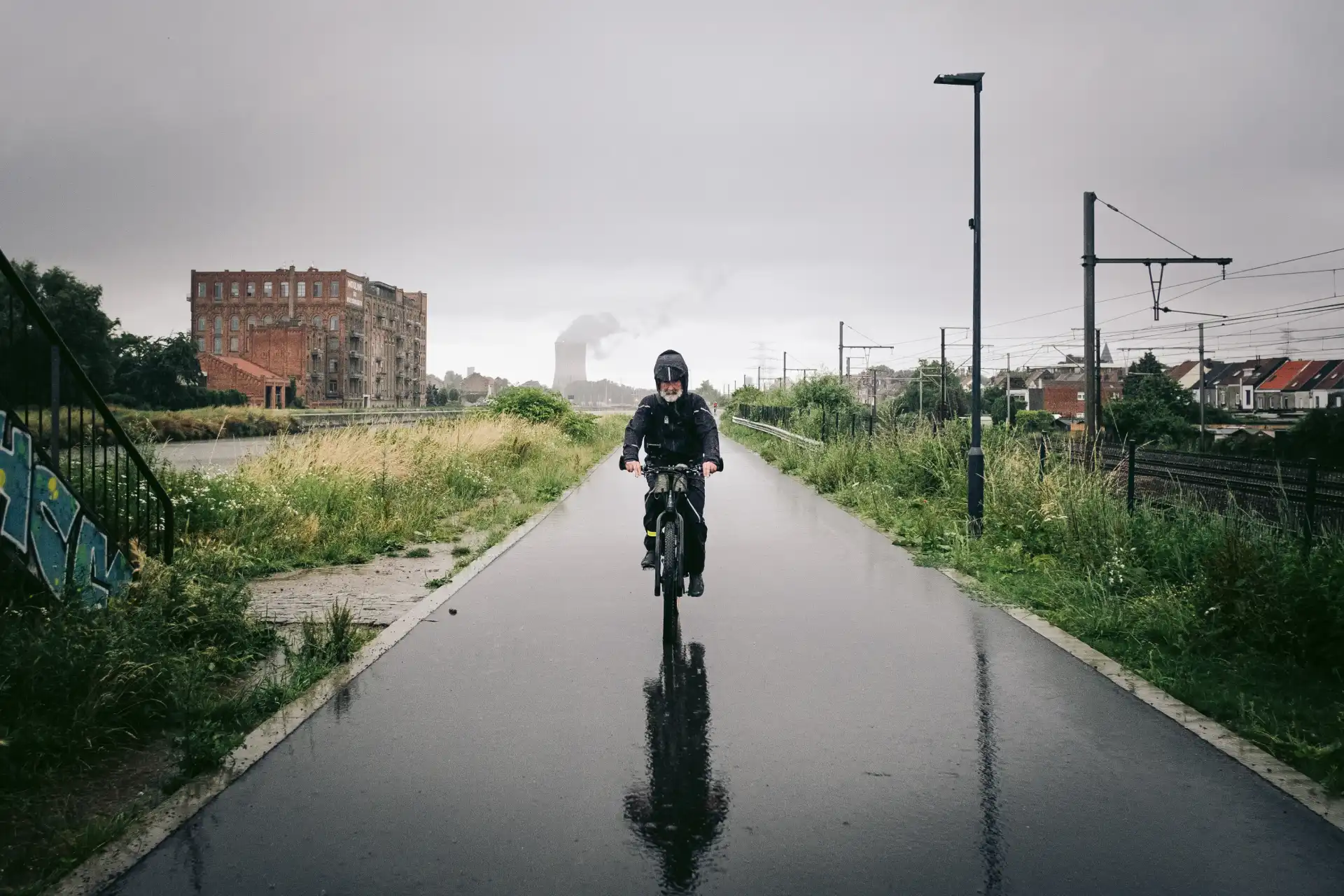 Fahrradfahren im Regen auf nasser Straße mit Regenbekleidung